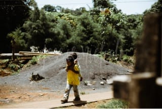 Child walking outside with toddler holding onto his back